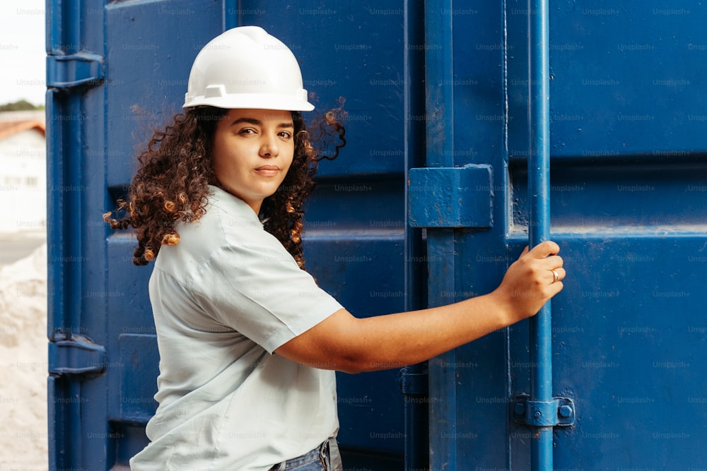 a woman wearing a hard hat and holding onto a blue container