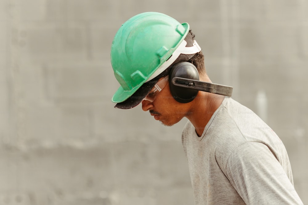 a man wearing a green hard hat and headphones