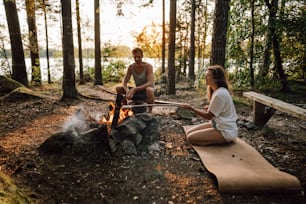 a man and a woman sitting around a campfire