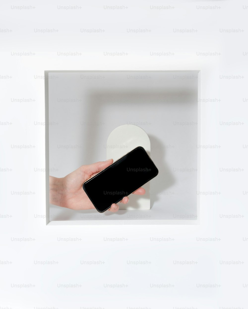 a person holding a cell phone in a white box