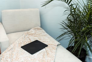 a laptop computer sitting on top of a bed next to a plant