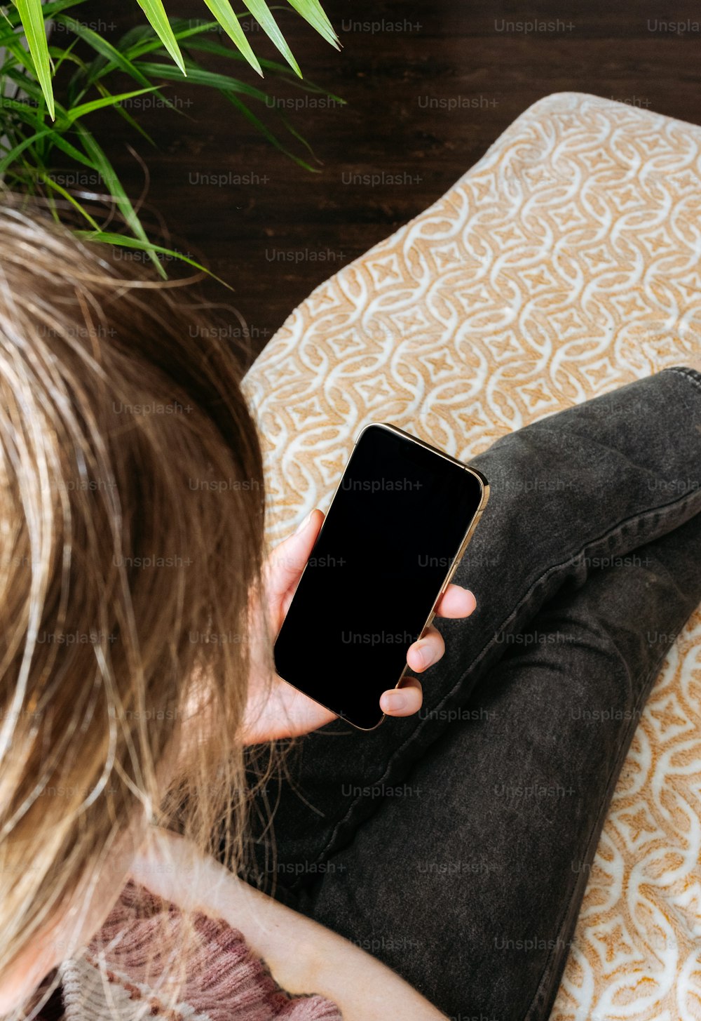 uma mulher sentada no chão olhando para seu telefone celular