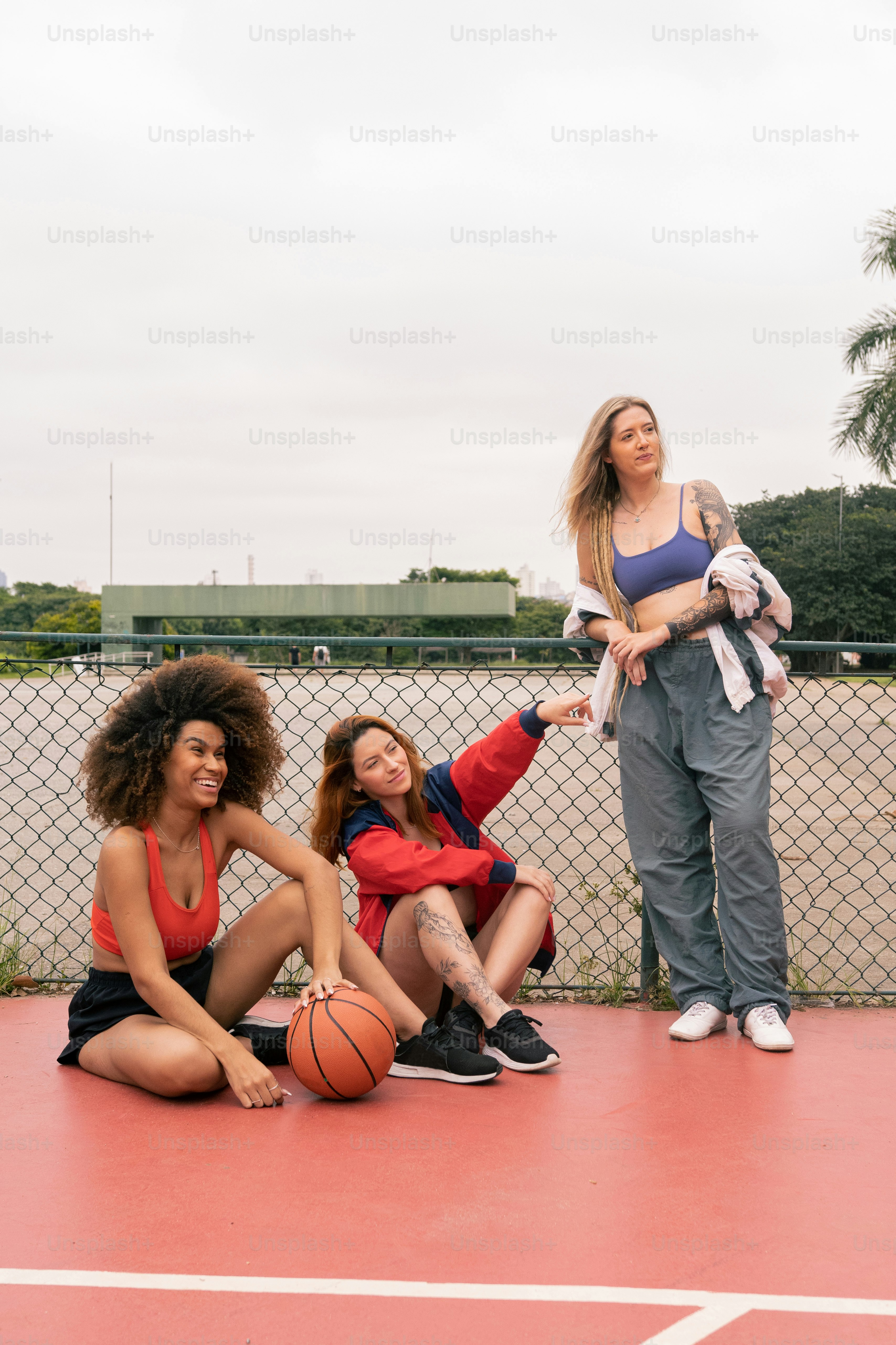 a group of women sitting on top of a basketball court