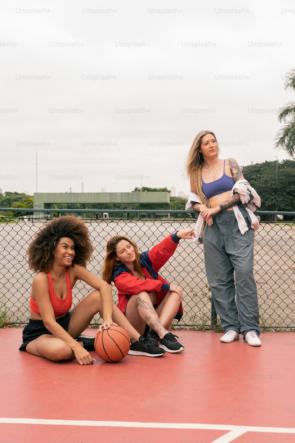 a group of women sitting on top of a basketball court
