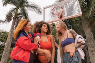 a group of women standing next to each other in front of a basketball hoop