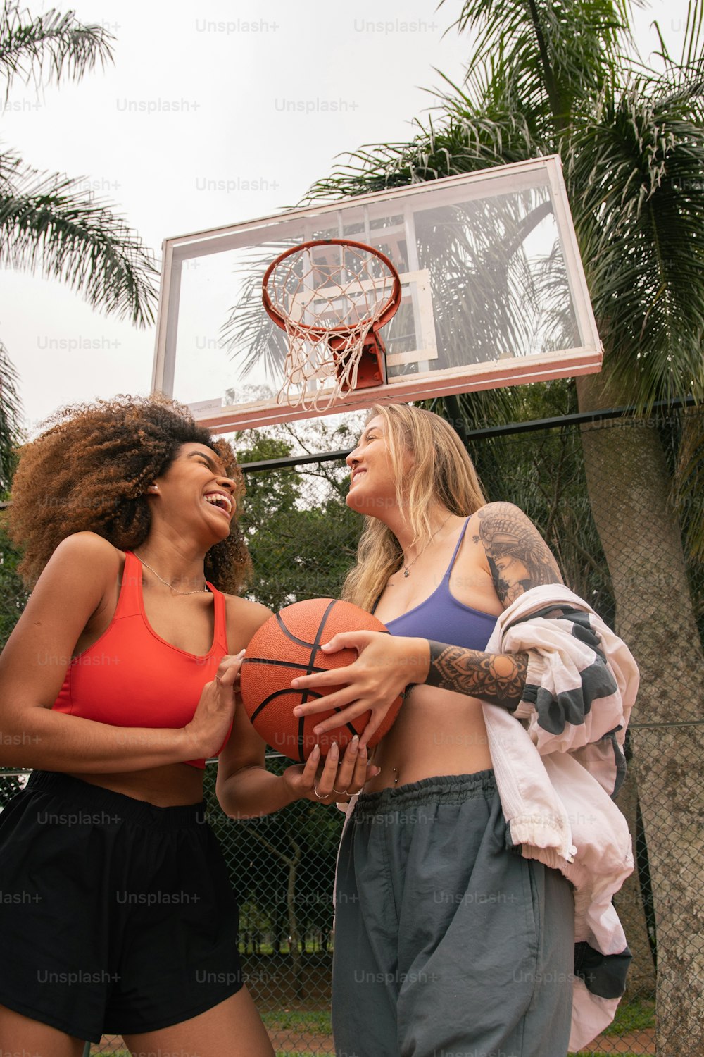 two women standing next to each other holding a basketball