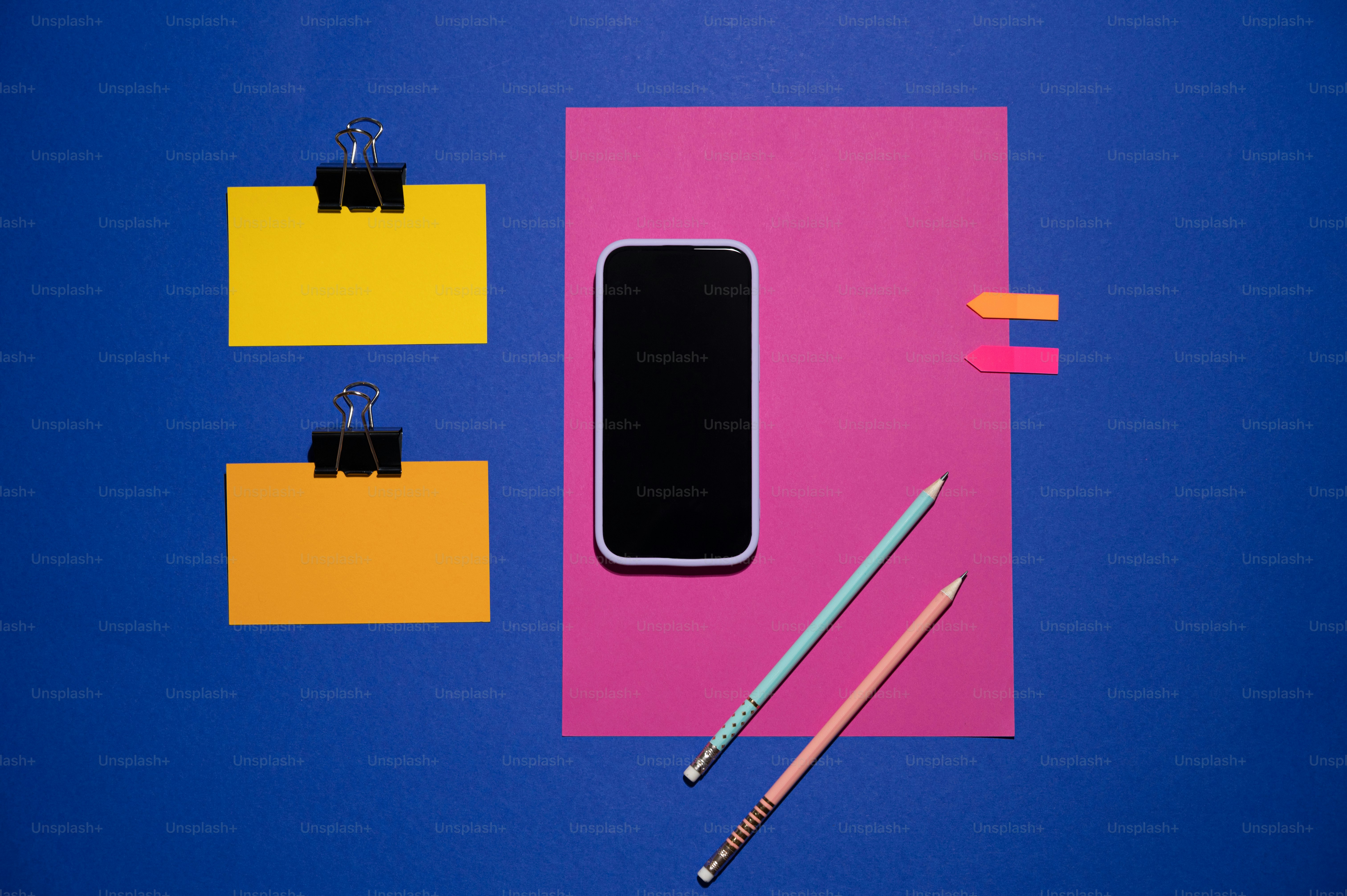 a cell phone sitting on top of a pink and yellow paper