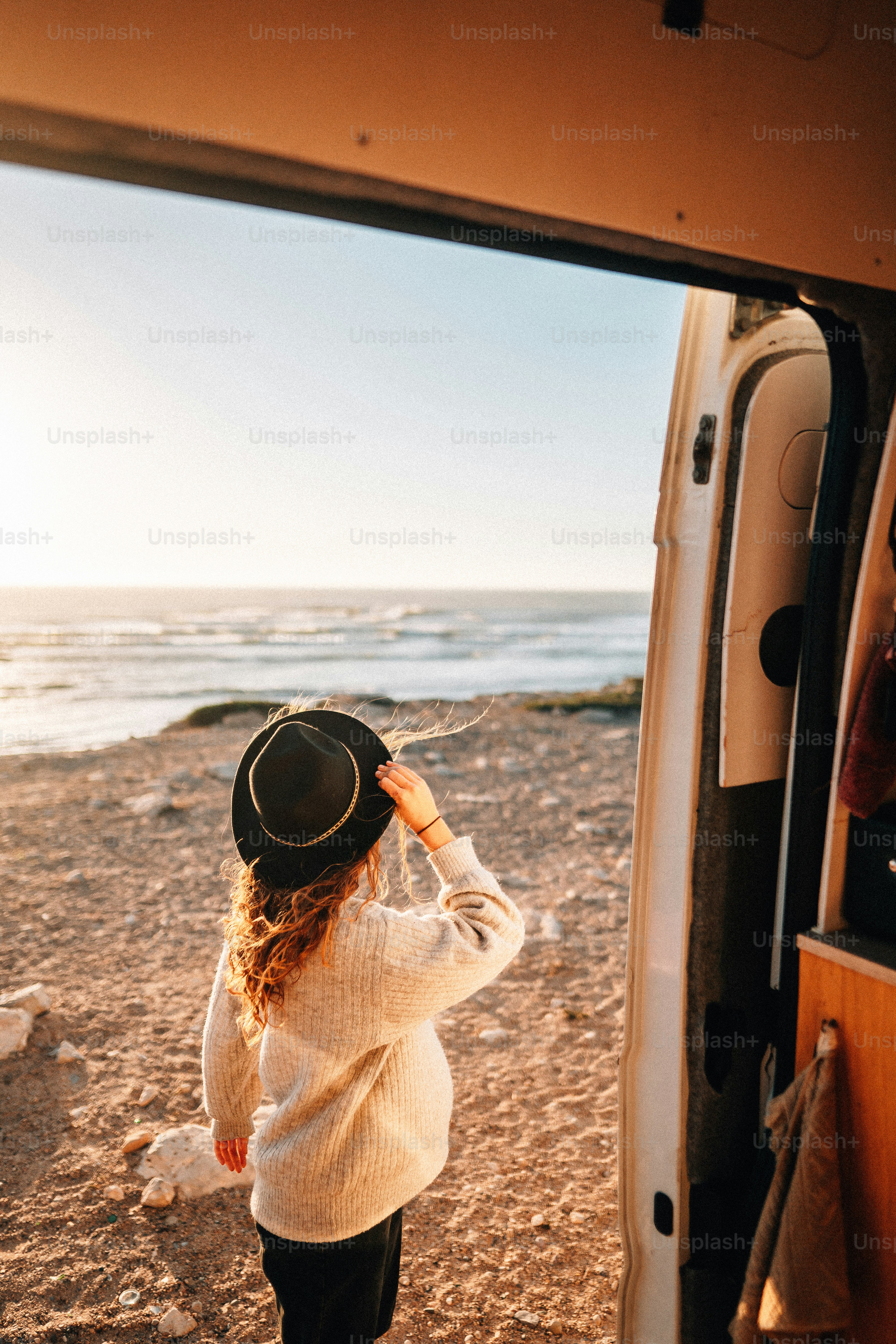 a woman standing on a beach next to a van