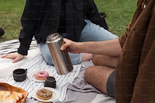a man sitting on a blanket holding a cup of coffee