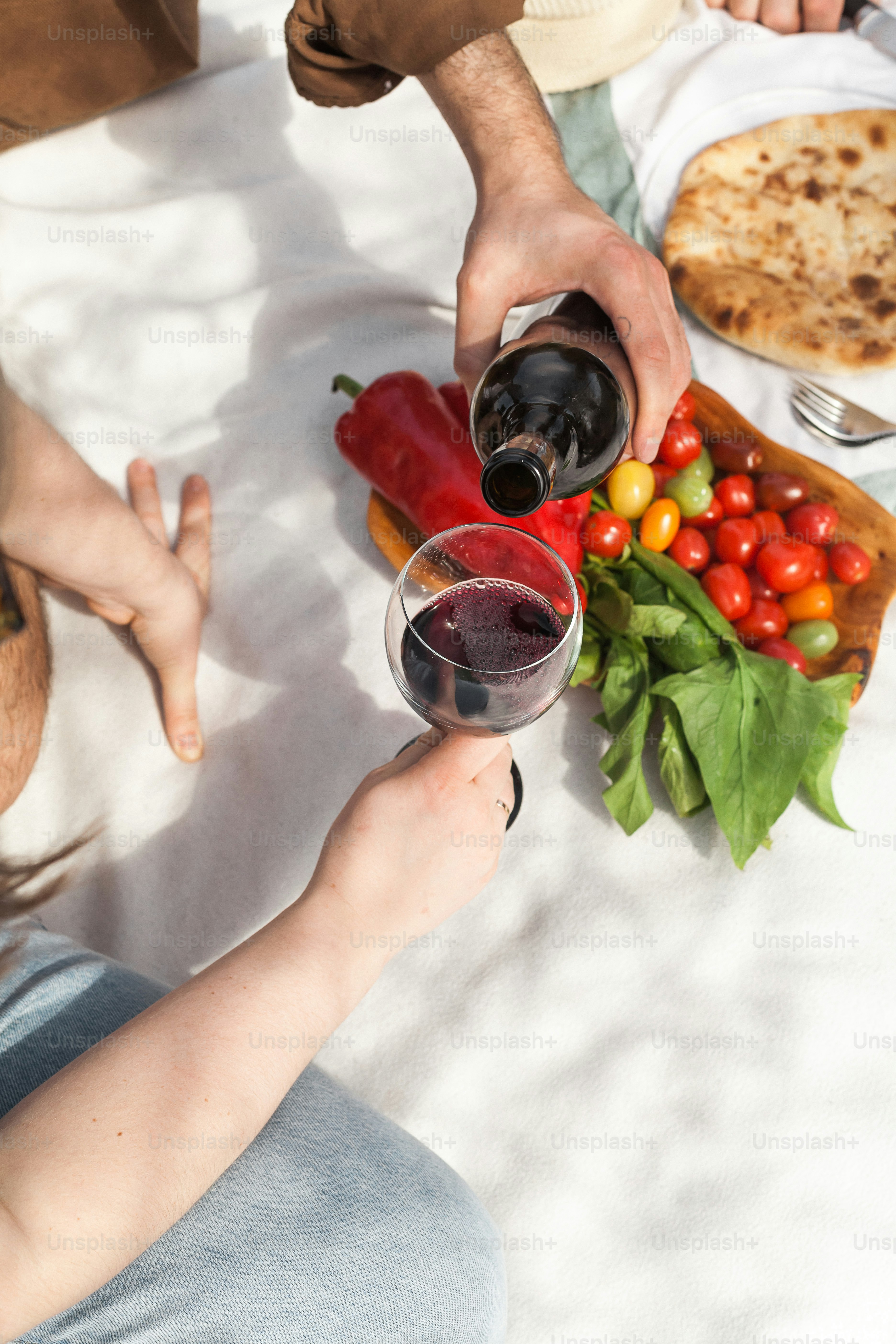 a man and a woman sitting at a table with food and wine