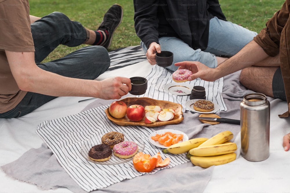 a group of people sitting on a blanket eating food