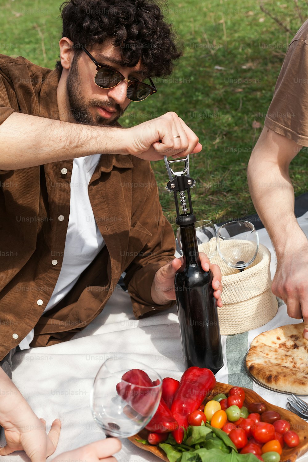 um homem segurando uma garrafa de vinho sobre um prato de comida