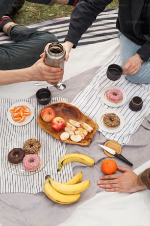 a group of people sitting around a table with donuts and fruit