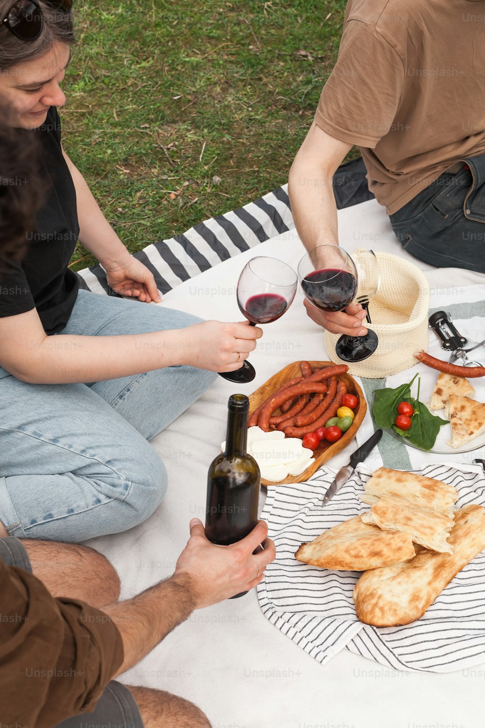 a group of people sitting around a table with food and wine