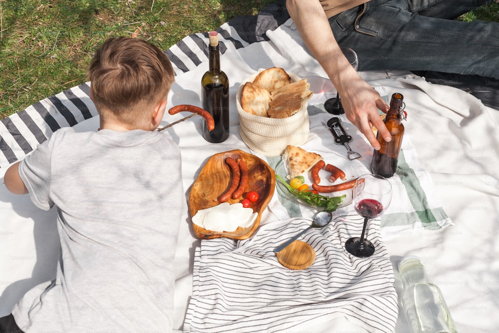 Ein Mann und ein Kind sitzen auf einer Decke bei einem Picknick