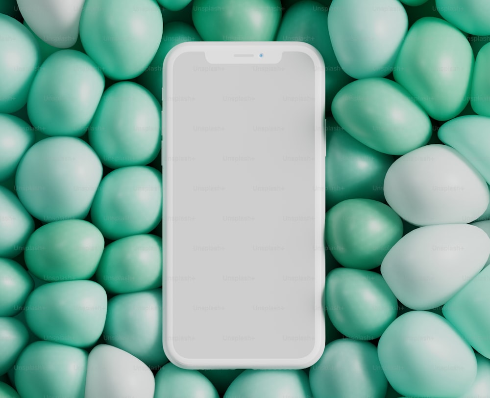 a white cell phone surrounded by green and white balls