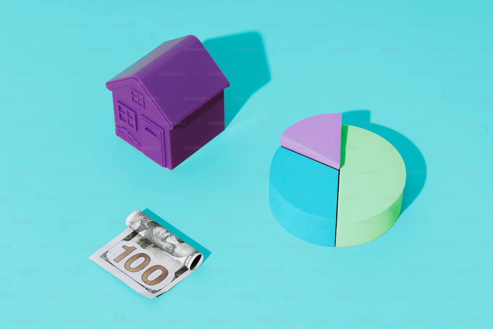a paper house next to a piece of money on a blue background