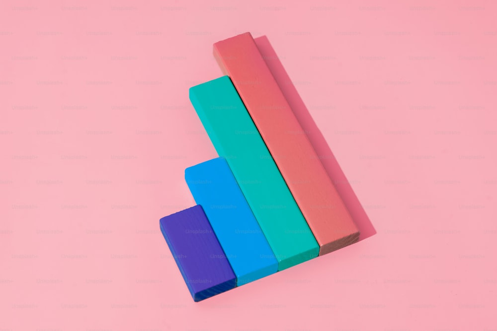 Una pila de bloques de colores sentados encima de una superficie rosa