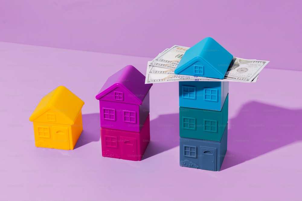 Tre piccole case sedute una accanto all'altra su una superficie viola
