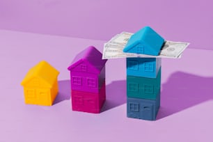 Tres pequeñas casas sentadas una al lado de la otra sobre una superficie púrpura