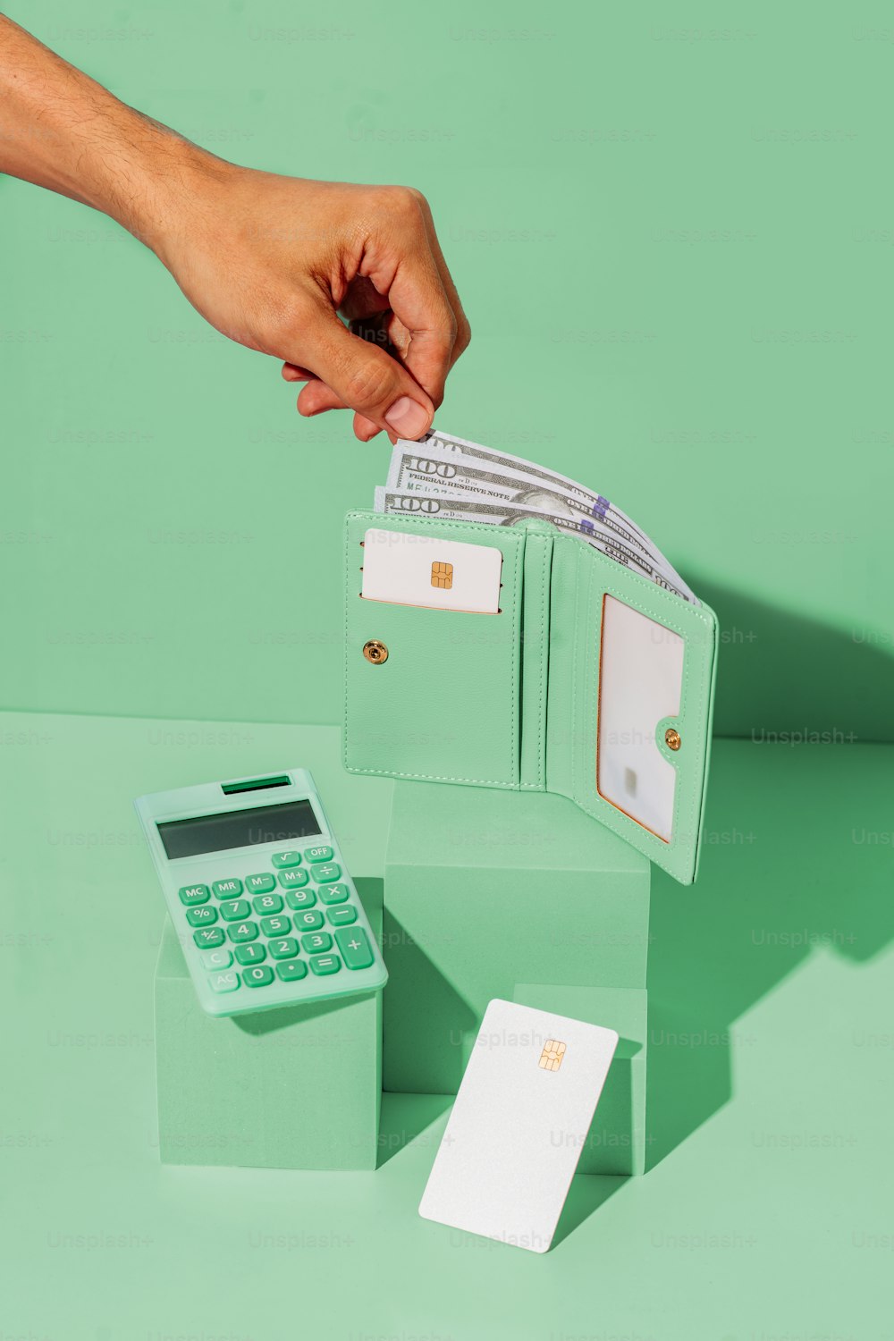 uma pessoa colocando dinheiro em uma carteira ao lado de uma calculadora