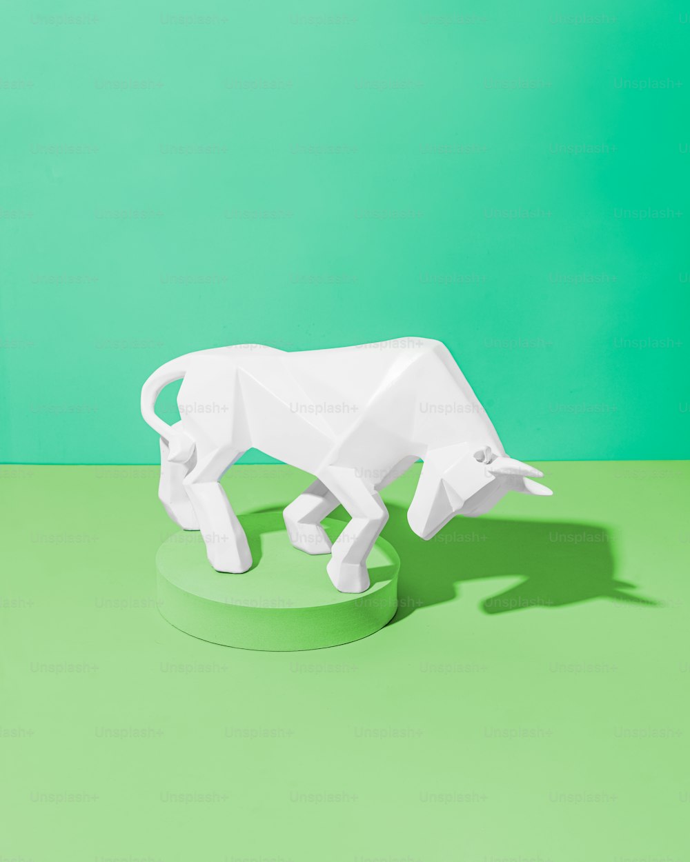 a white sculpture of a bull on a green surface