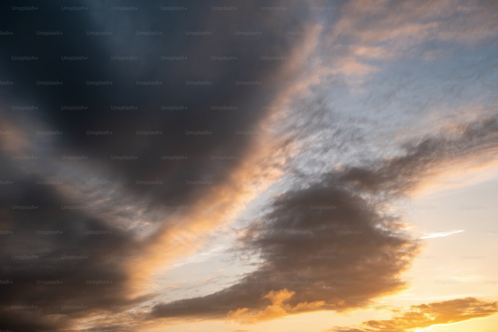 a plane flying through a cloudy sky at sunset