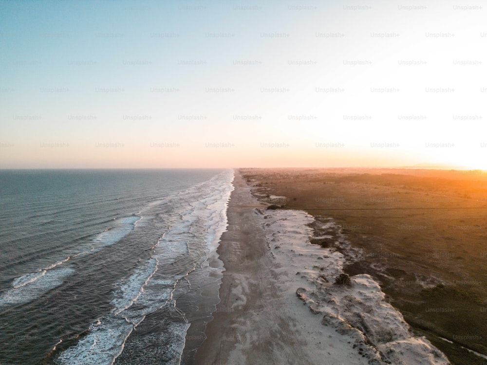 uma vista aérea de uma praia ao pôr do sol