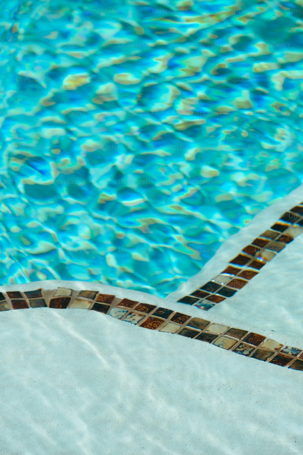 uma piscina com uma borda de azulejo e água azul
