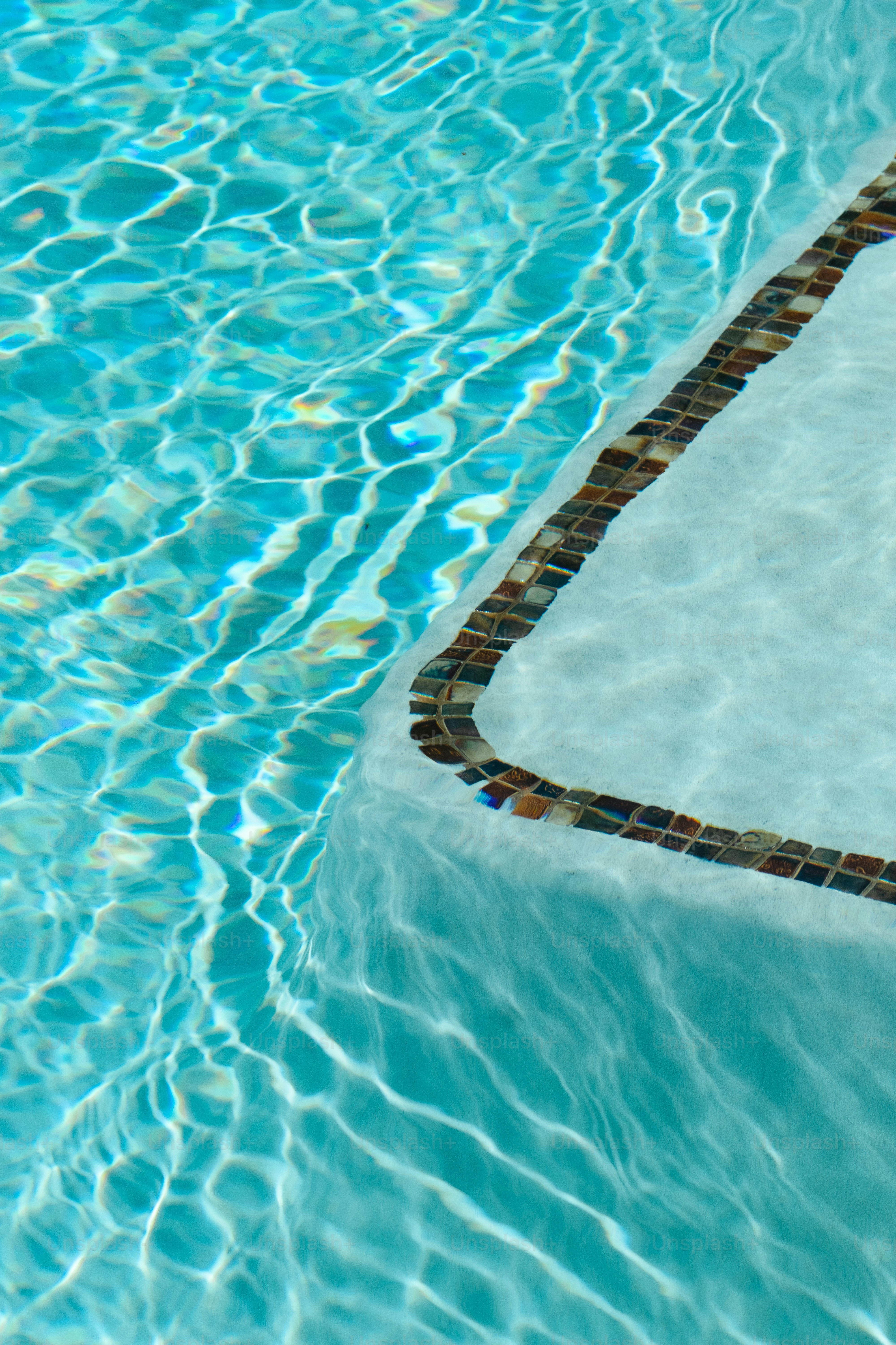 a swimming pool with a tiled edge and blue water