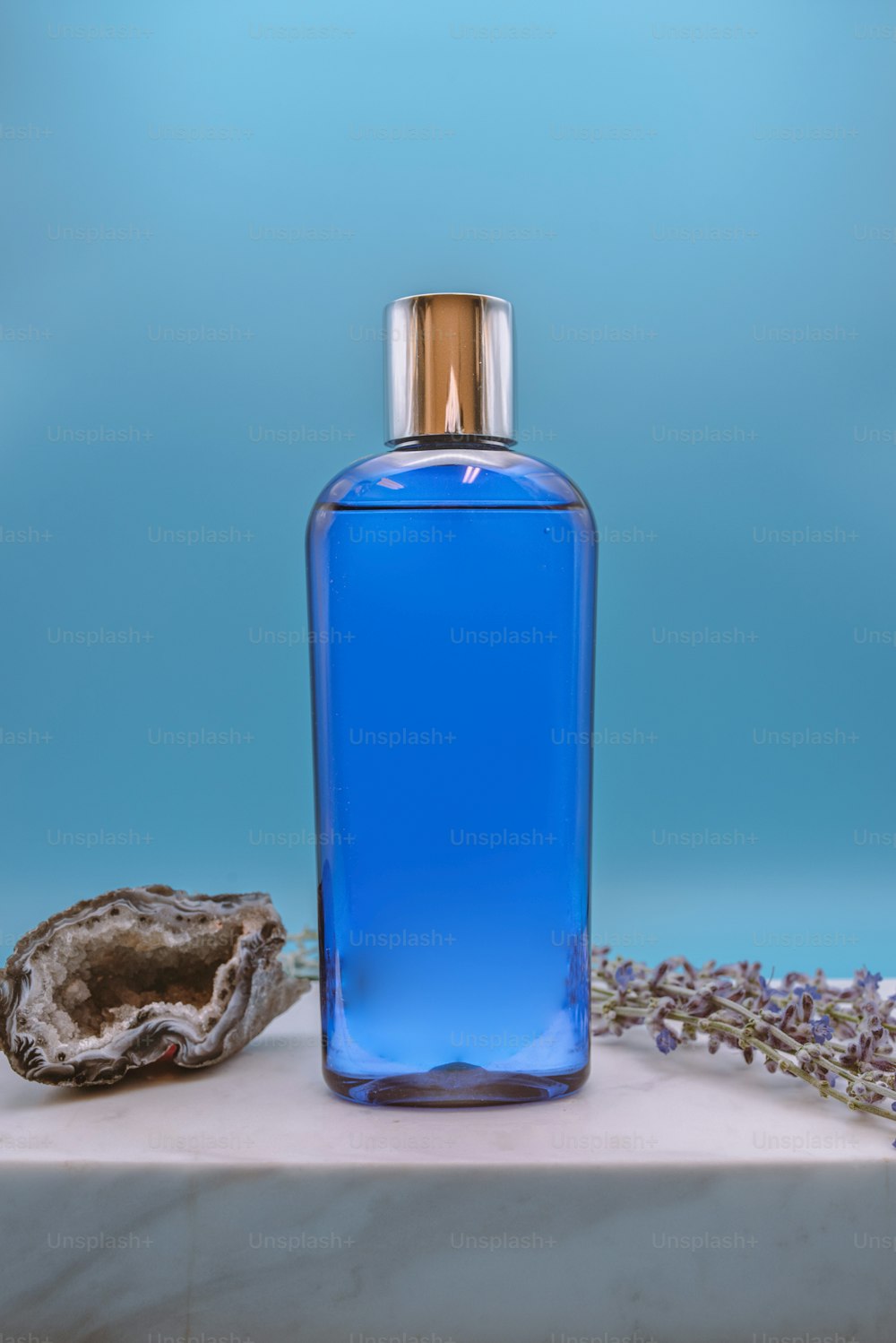 a bottle of blue liquid next to a rock