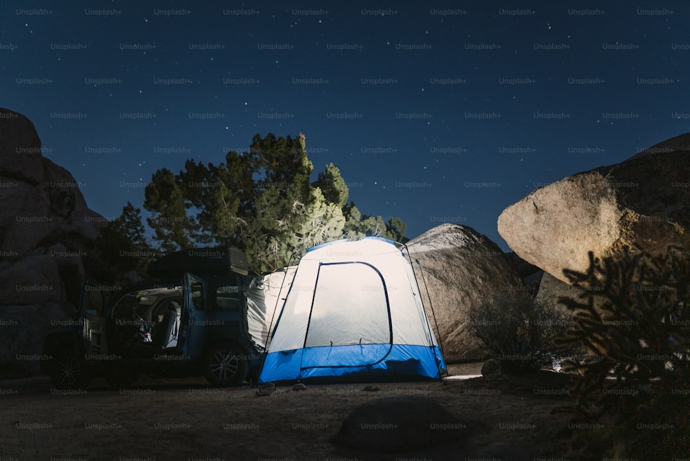uma tenda azul e branca e algumas rochas e árvores
