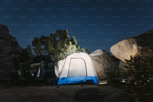 a blue and white tent and some rocks and trees