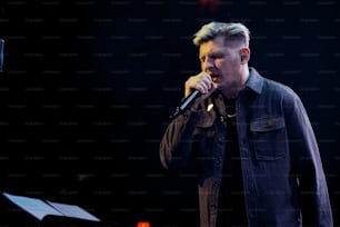 Ein Mann, der auf der Bühne in ein Mikrofon singt
