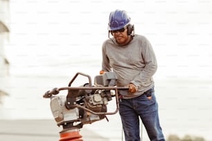 a man wearing a hard hat and holding a machine