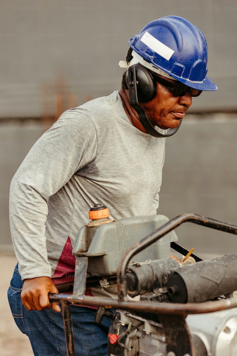 a man wearing a hard hat and holding a machine