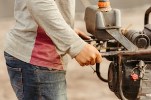 um homem segurando um pequeno motor com uma chave inglesa