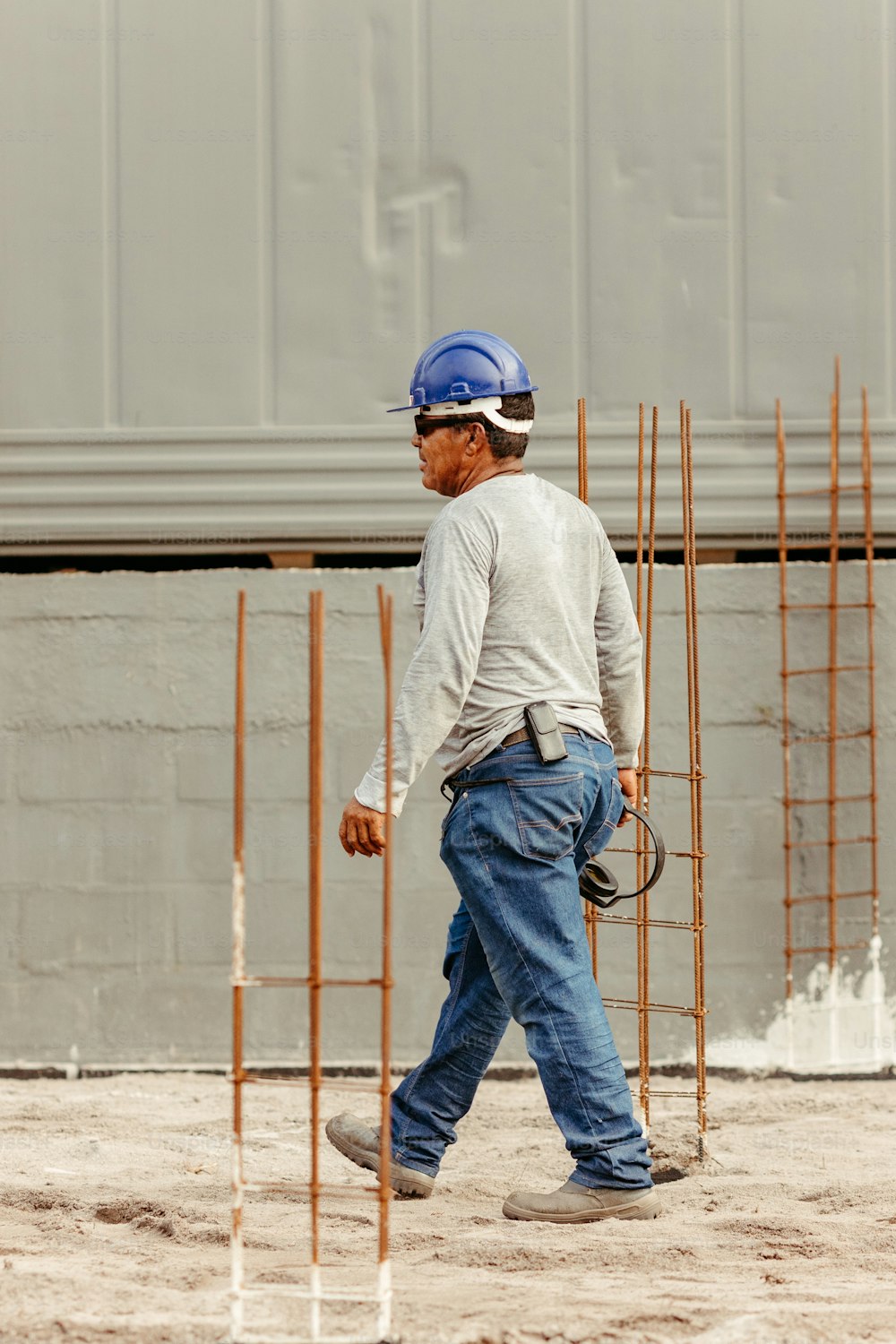 Un homme portant un casque de sécurité passant devant un chantier de construction