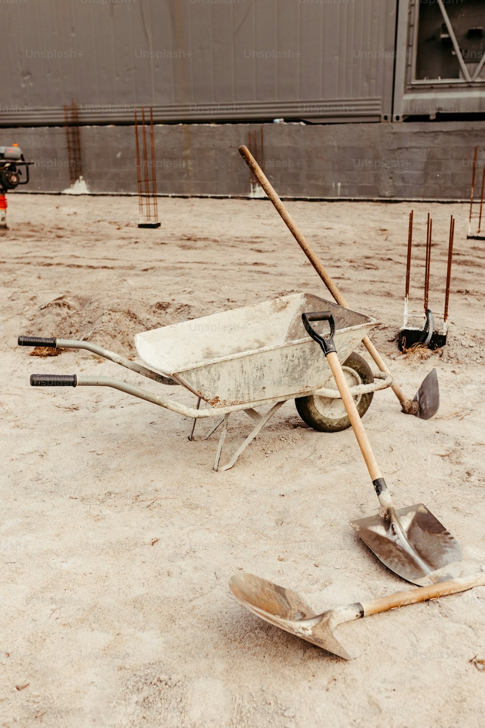a wheelbarrow, shovels, and shovels are laying on the ground