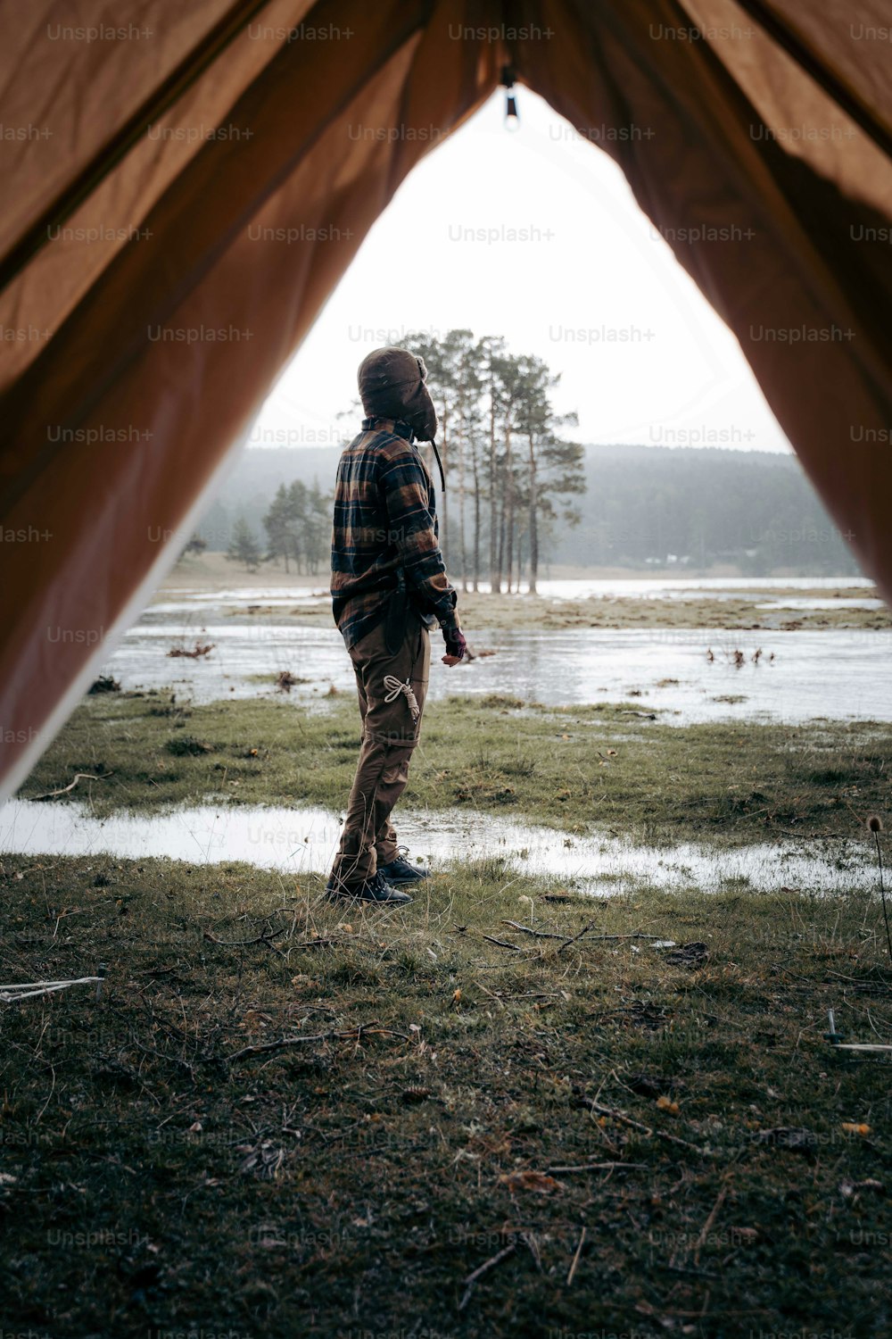 a man standing inside of a tent next to a lake