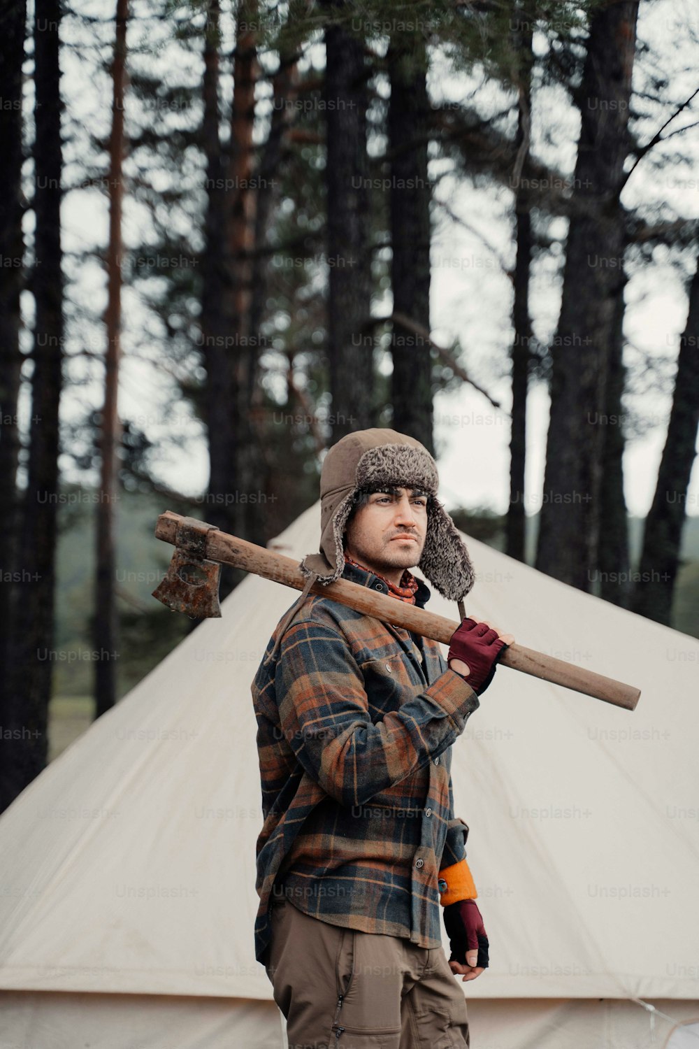 a man holding a large axe in front of a tent