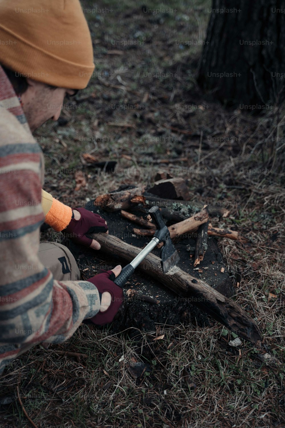 a man in a striped shirt chopping wood with a knife