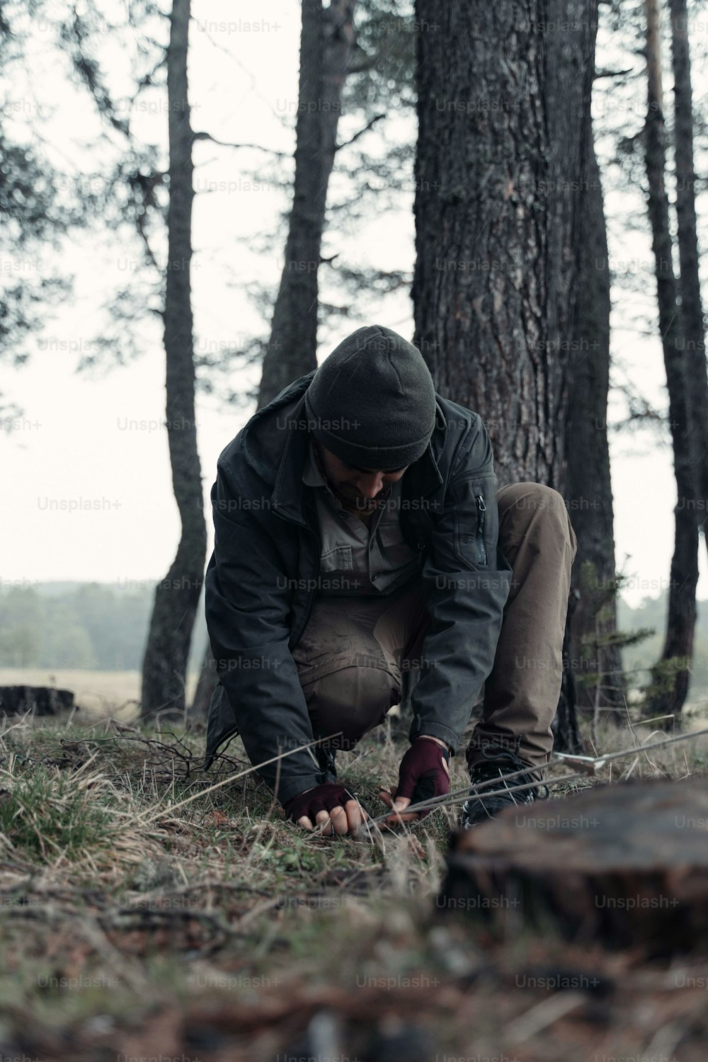 a man kneeling down in the woods looking at something