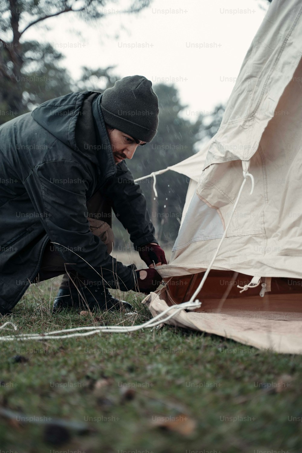 a man working on a tent in the grass
