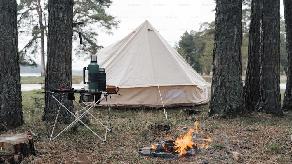 a tent is set up next to a campfire