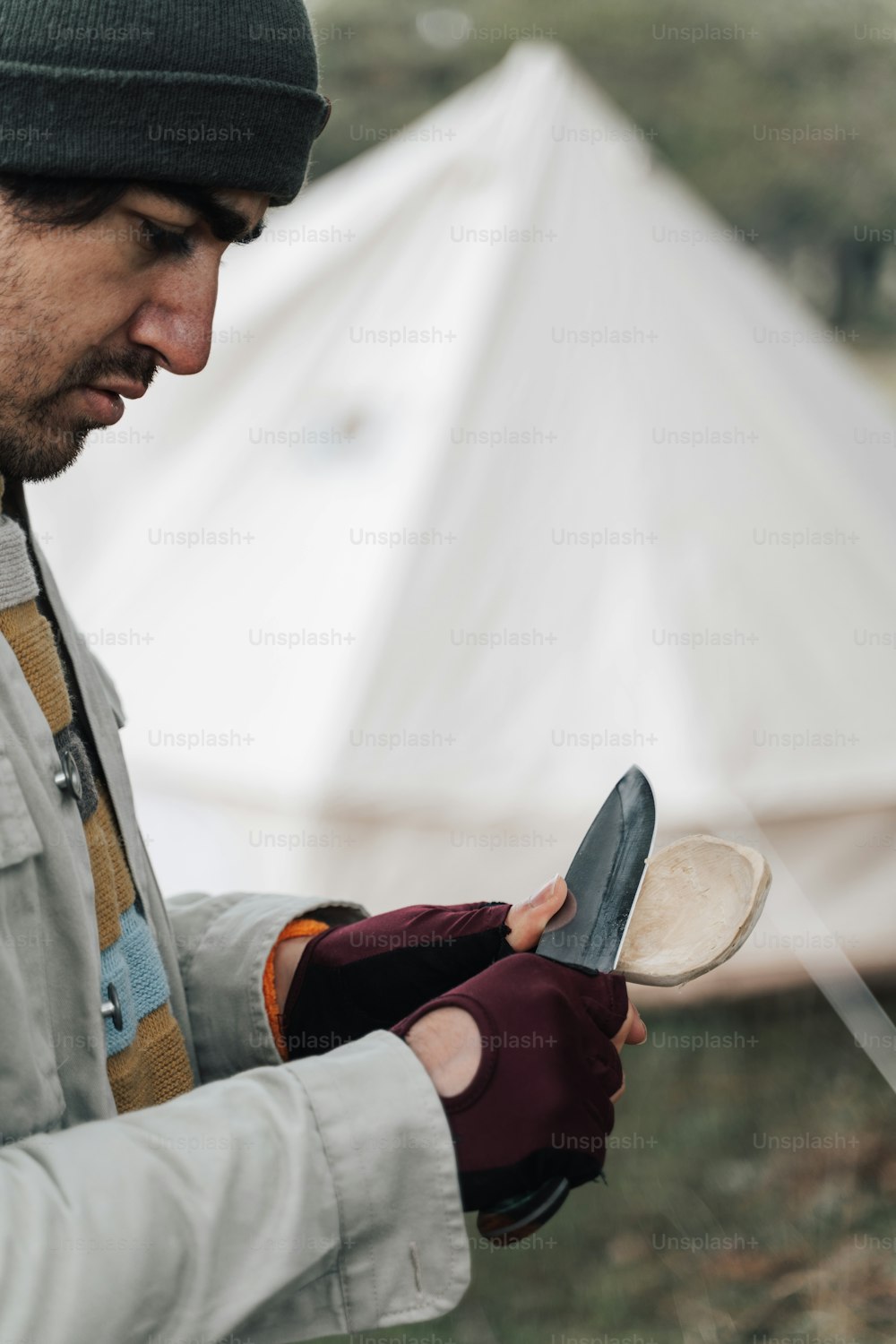 a man holding a pair of gloves while standing next to a tent