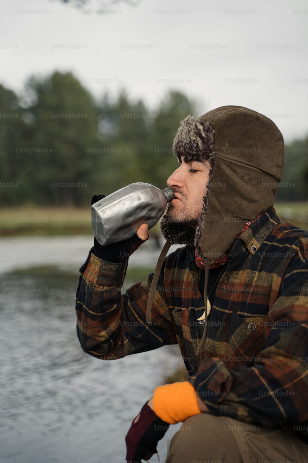 Ein Mann mit Hut, der aus einer Wasserflasche trinkt