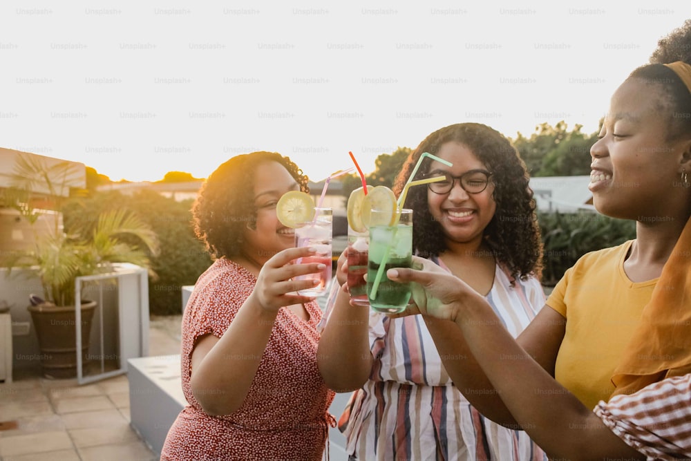 a group of women standing next to each other holding drinks