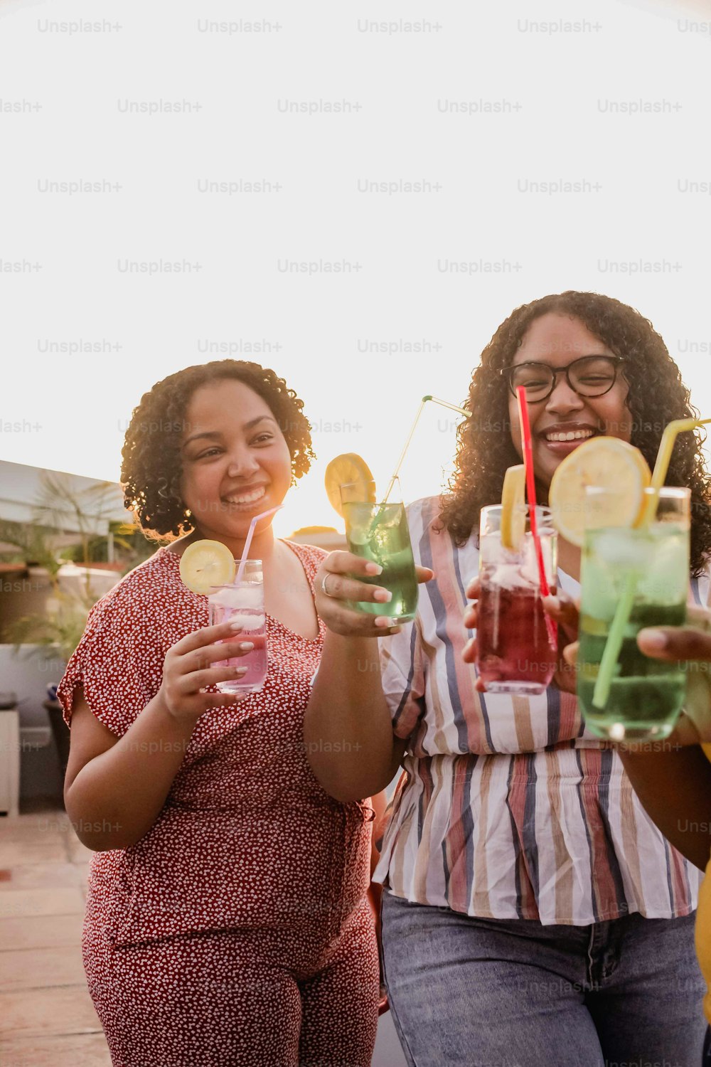 a group of women standing next to each other holding drinks