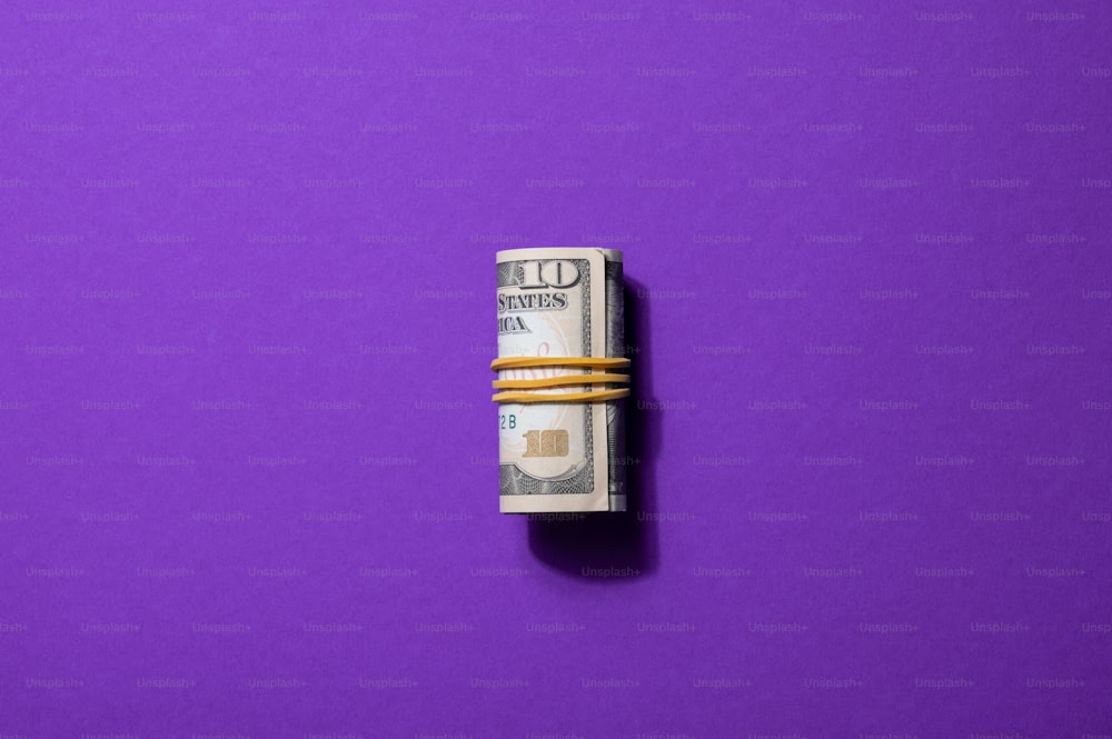 une pile de billets de cent dollars sur fond violet